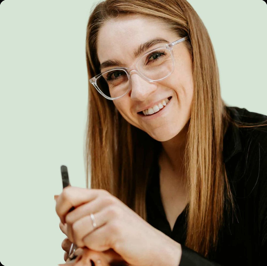 Jess, lash educator at Your Fan Club, smiling while holding a lash tool against a light green background