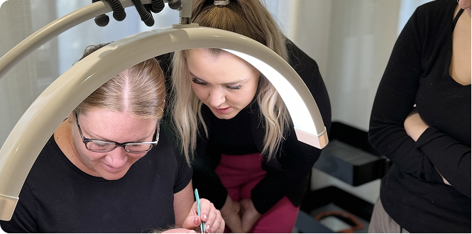 Your Fan Club lash trainer teaching a student how to apply lash extensions during an in-person training session.