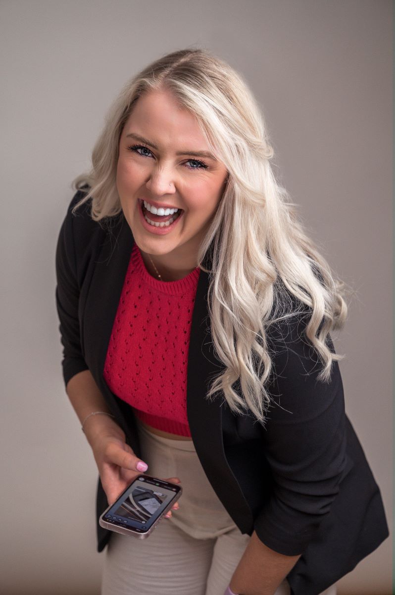 Flic, founder of Your Fan Club, smiling and holding her phone.